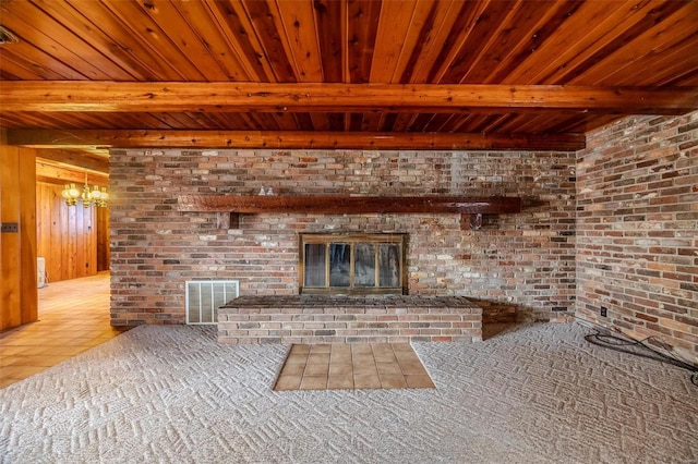 unfurnished living room with wood ceiling, a brick fireplace, beam ceiling, and brick wall