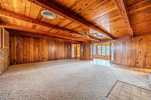 unfurnished living room featuring wooden walls, ceiling fan, wood ceiling, light carpet, and beam ceiling