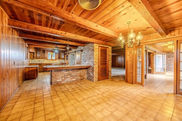 kitchen featuring a chandelier, wooden walls, kitchen peninsula, and hanging light fixtures