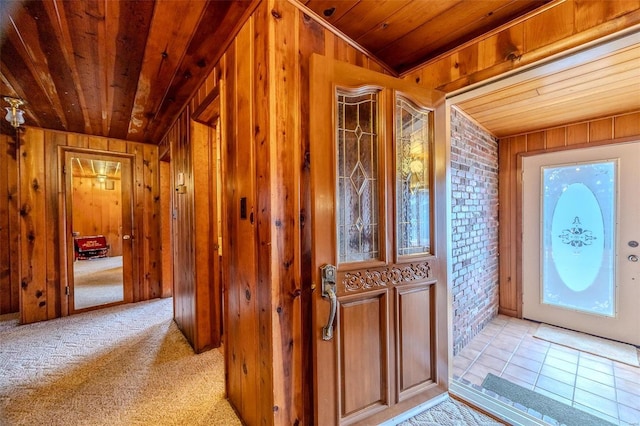 entryway featuring brick wall, wooden walls, light carpet, and wood ceiling