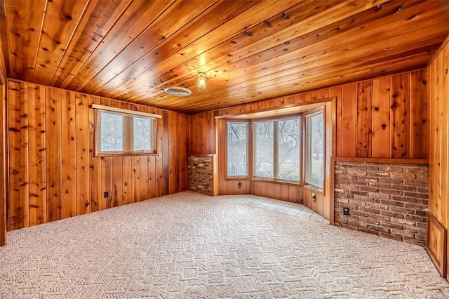 carpeted spare room with wooden ceiling and wood walls