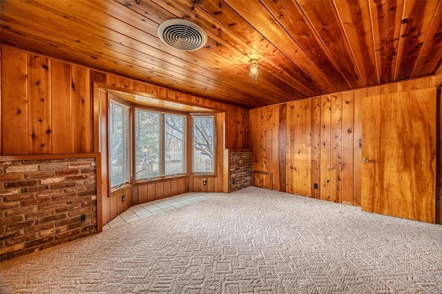 empty room featuring wood ceiling, light colored carpet, and wooden walls