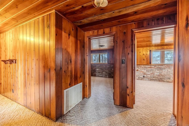 hall featuring brick wall, carpet floors, wood ceiling, and wooden walls