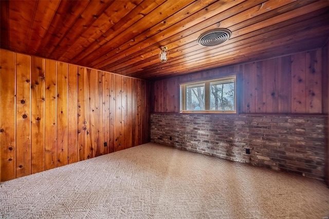 spare room with wood walls, brick wall, carpet flooring, and wooden ceiling