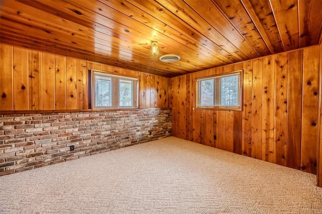 carpeted empty room featuring brick wall, wood ceiling, and wood walls