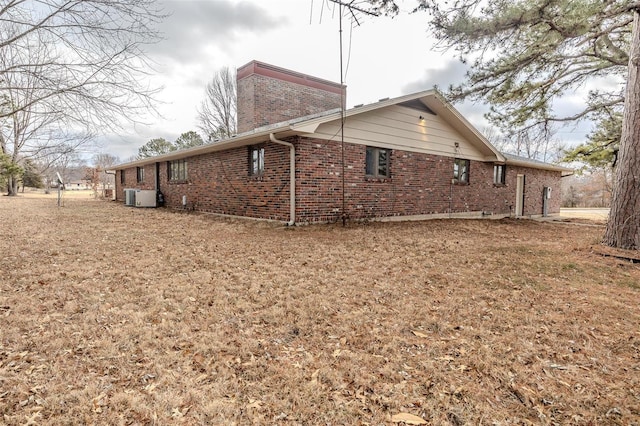 view of property exterior with central AC and a yard