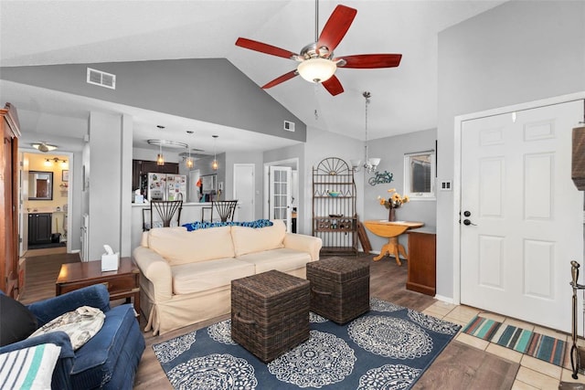 living room with vaulted ceiling, ceiling fan with notable chandelier, and light hardwood / wood-style floors