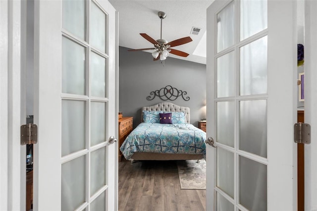 bedroom featuring french doors, lofted ceiling, wood-type flooring, a textured ceiling, and ceiling fan