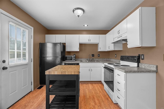 kitchen with range with electric cooktop, sink, white cabinets, black fridge, and light hardwood / wood-style flooring