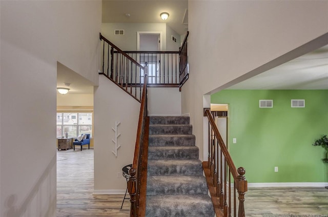 staircase featuring hardwood / wood-style flooring and a high ceiling