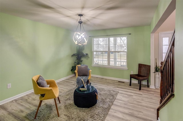 living area with an inviting chandelier, plenty of natural light, and light wood-type flooring