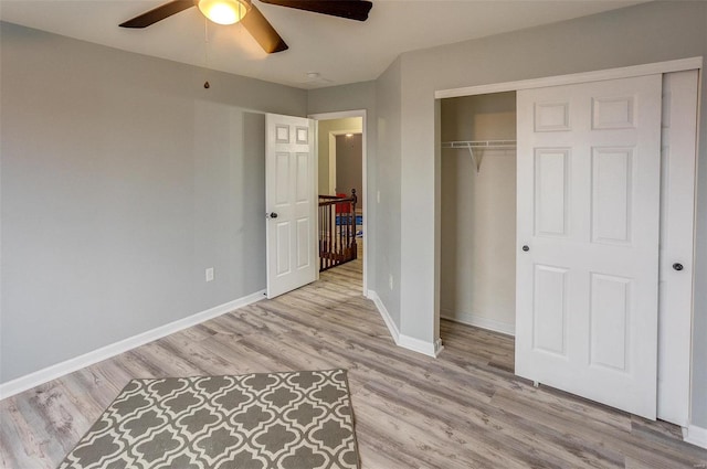 unfurnished bedroom featuring ceiling fan, light hardwood / wood-style floors, and a closet