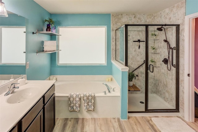 bathroom with wood-type flooring, shower with separate bathtub, and vanity