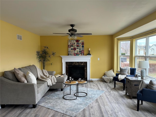 living room with ceiling fan, a fireplace, and light hardwood / wood-style floors