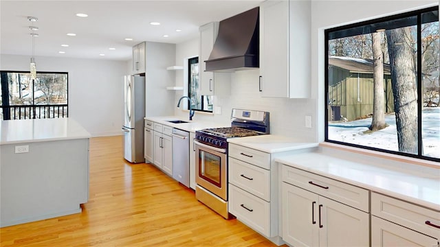 kitchen featuring pendant lighting, sink, premium range hood, appliances with stainless steel finishes, and white cabinets