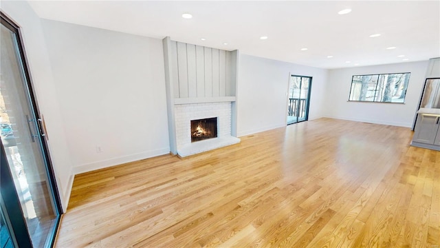 unfurnished living room with a brick fireplace and light hardwood / wood-style floors