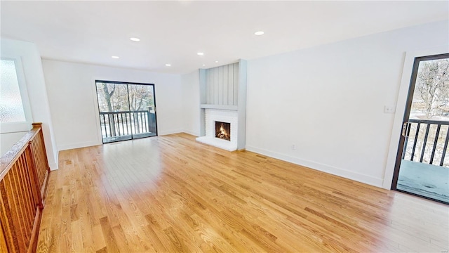 unfurnished living room with a brick fireplace and light hardwood / wood-style floors