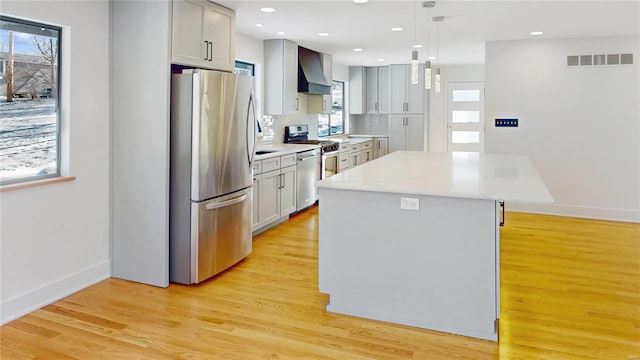 kitchen with decorative light fixtures, a center island, appliances with stainless steel finishes, custom range hood, and backsplash