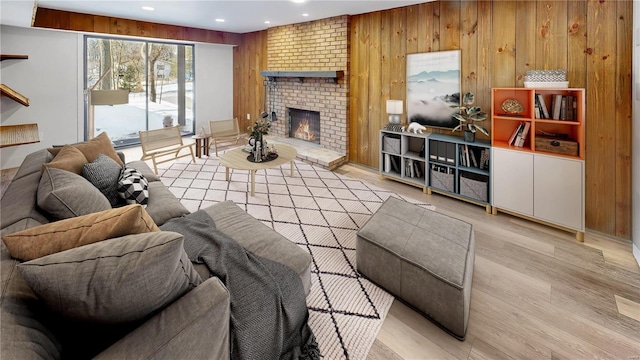 living room featuring a fireplace, light hardwood / wood-style floors, and wood walls