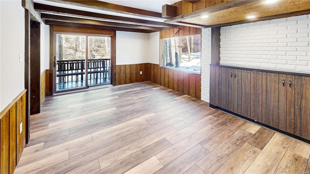 spare room featuring beam ceiling and light hardwood / wood-style flooring