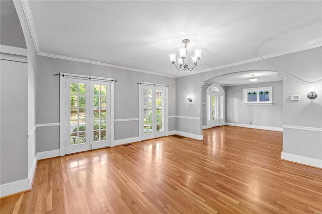 unfurnished room with ornamental molding, a chandelier, and light wood-type flooring