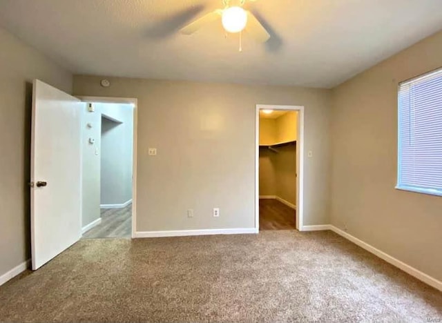 unfurnished bedroom with a spacious closet, light carpet, ceiling fan, and a closet