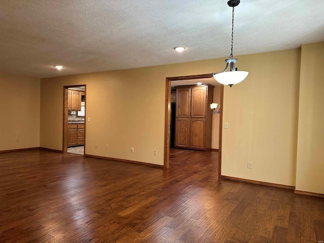 empty room with dark wood-type flooring and a textured ceiling