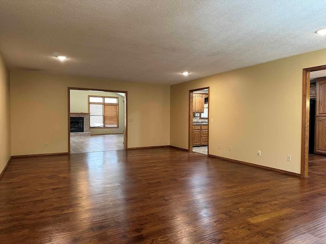 spare room with a fireplace, dark wood-type flooring, and a textured ceiling