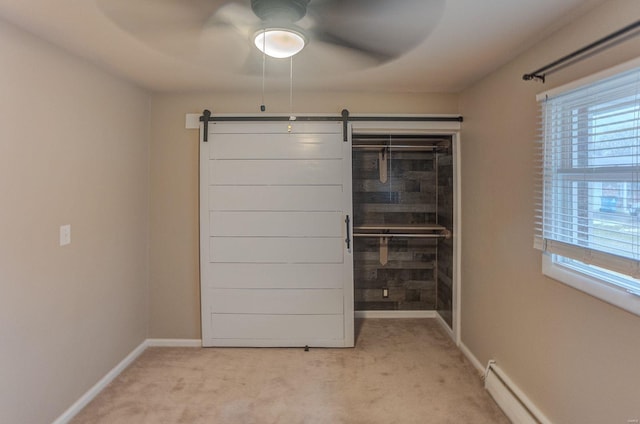 unfurnished bedroom featuring light colored carpet, a closet, ceiling fan, a barn door, and a baseboard heating unit