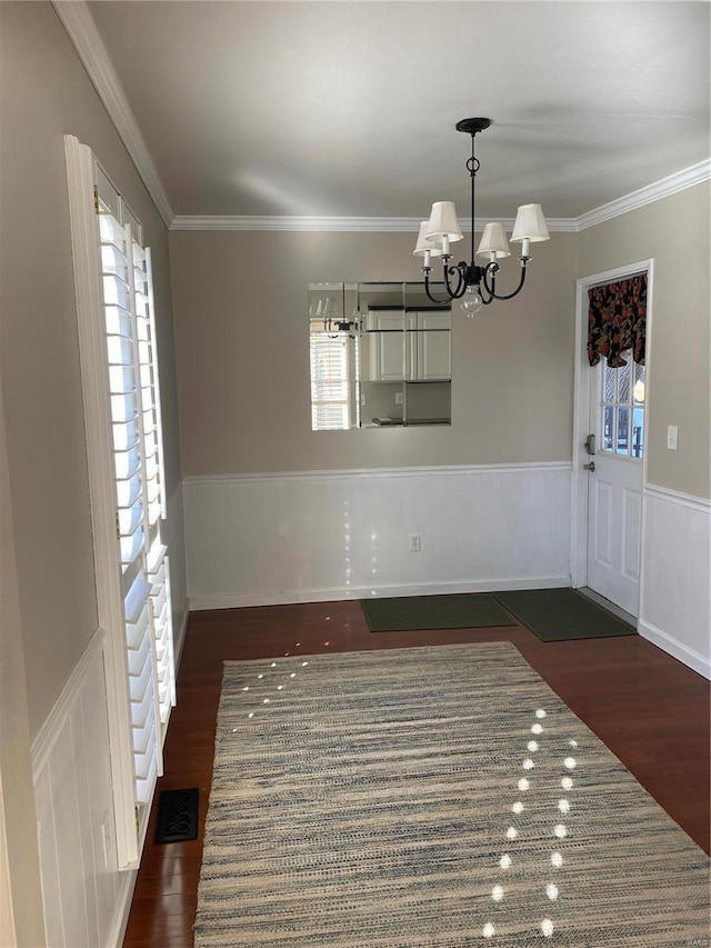 unfurnished dining area with dark hardwood / wood-style floors, ornamental molding, a healthy amount of sunlight, and a chandelier