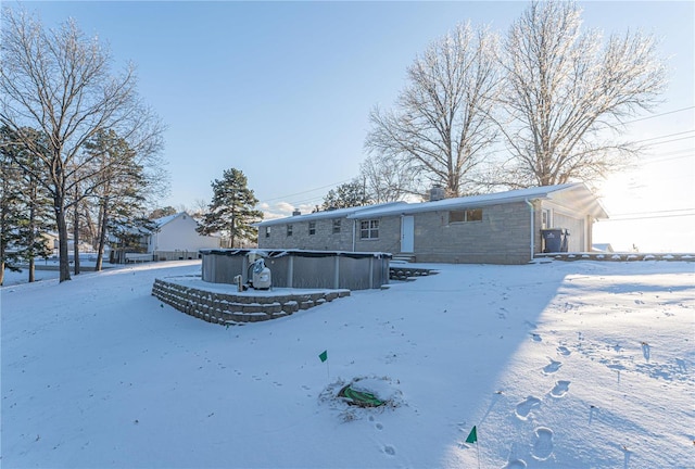 snow covered rear of property featuring a garage