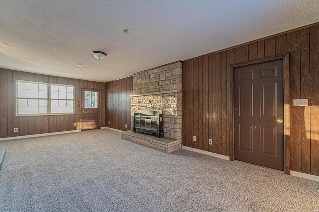 unfurnished living room with carpet floors, a textured ceiling, and wooden walls