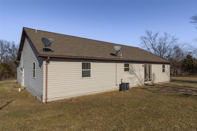 back of property with central AC unit and a lawn