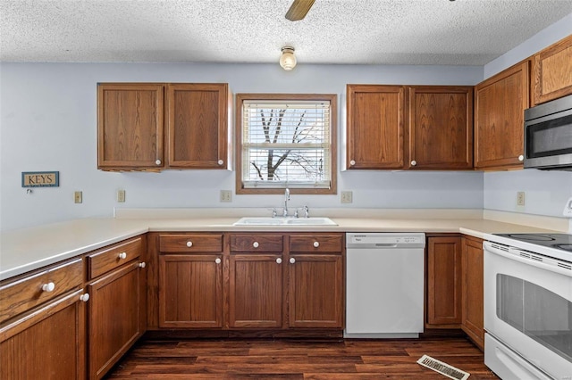 kitchen with sink, white appliances, dark hardwood / wood-style floors, and a textured ceiling