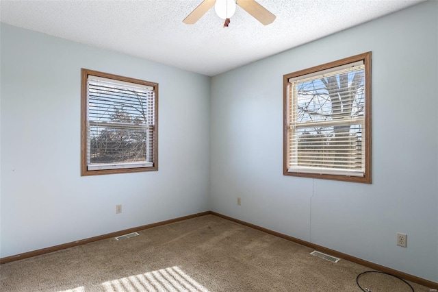 empty room featuring ceiling fan, carpet flooring, and a textured ceiling