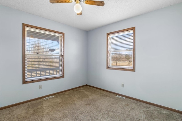 carpeted spare room featuring ceiling fan and a textured ceiling