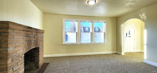 unfurnished living room featuring a brick fireplace and carpet floors