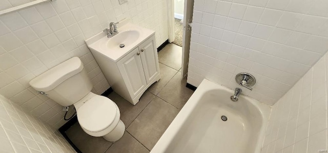 bathroom with tile patterned floors, toilet, tile walls, vanity, and a bathing tub