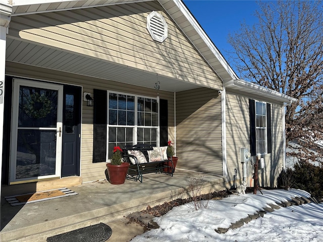 snow covered property entrance featuring a porch