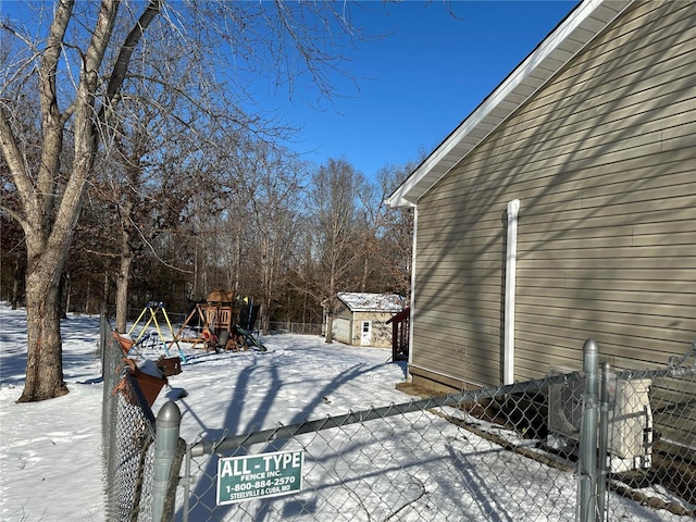 snow covered patio featuring a storage unit and a playground