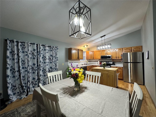 dining space with lofted ceiling and light wood-style floors