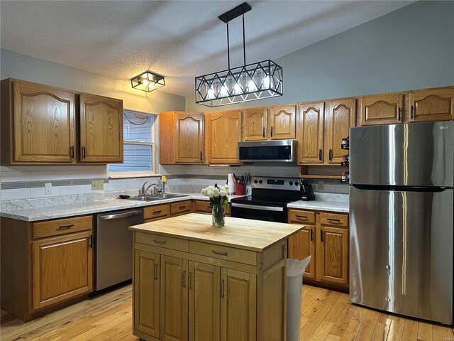 kitchen featuring stainless steel appliances, butcher block countertops, a sink, light wood-type flooring, and brown cabinets