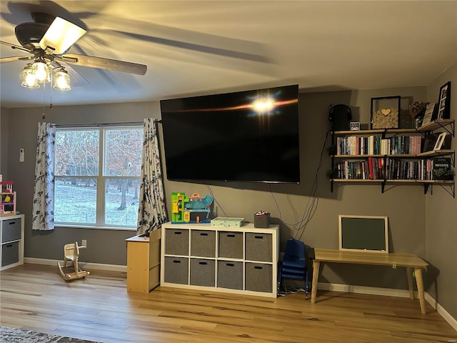 game room with light wood-type flooring, ceiling fan, and baseboards