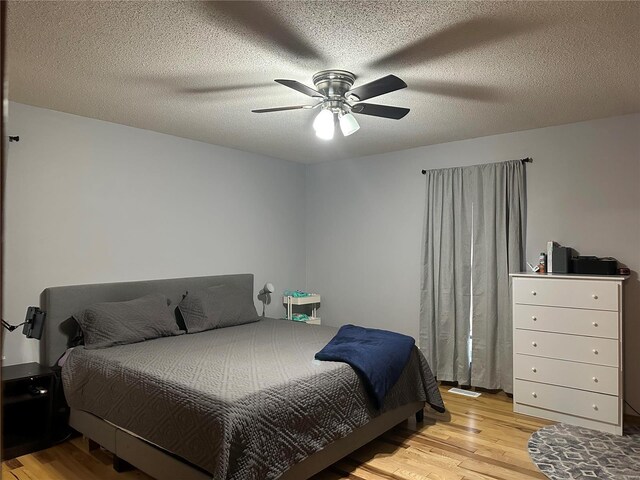 bedroom featuring a ceiling fan, a textured ceiling, and light wood finished floors