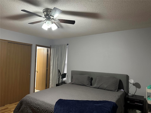 bedroom featuring light wood-style flooring, a textured ceiling, and a ceiling fan