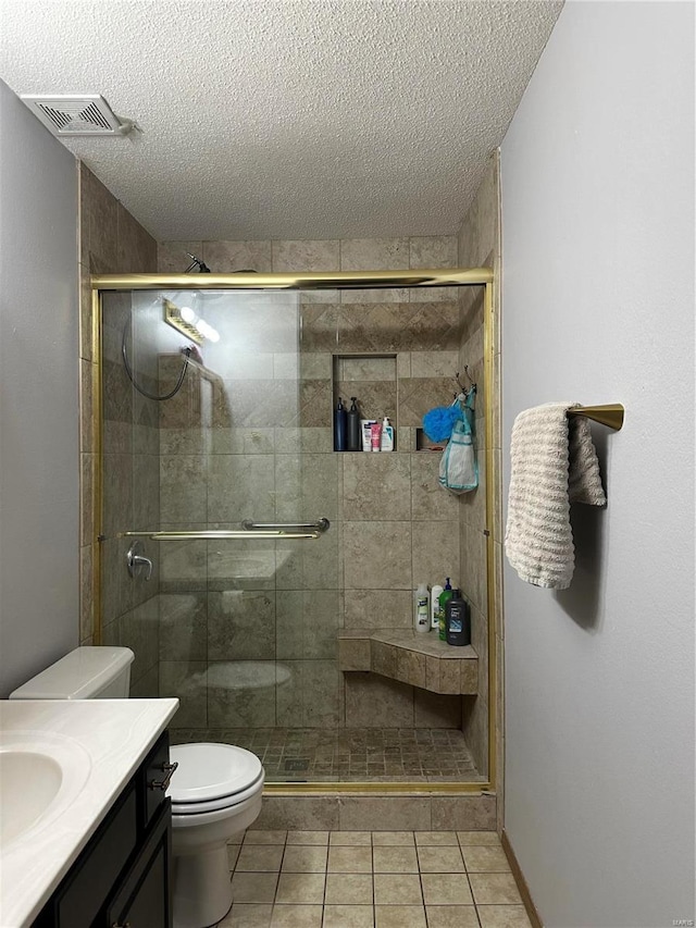 bathroom with visible vents, toilet, a stall shower, vanity, and a textured ceiling