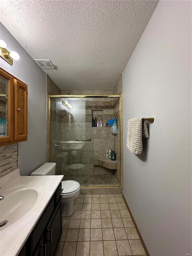 bathroom with toilet, a shower stall, a textured ceiling, and vanity