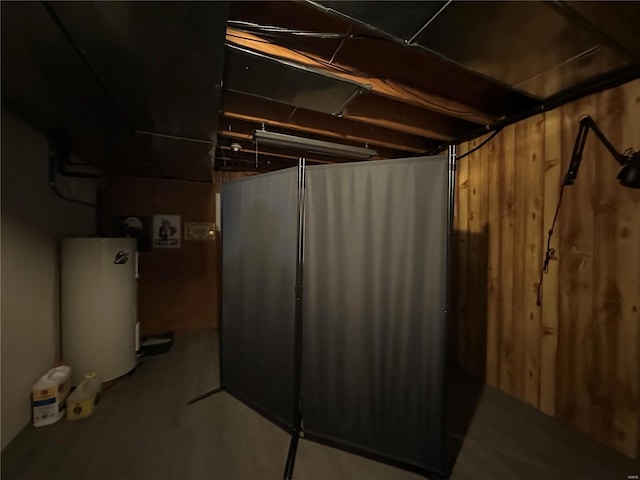 unfinished below grade area featuring wooden walls and water heater