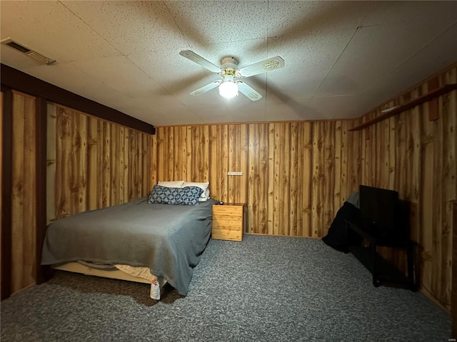 carpeted bedroom featuring ceiling fan, visible vents, and wooden walls