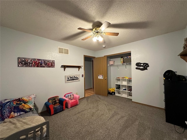 recreation room with carpet, ceiling fan, visible vents, and a textured ceiling